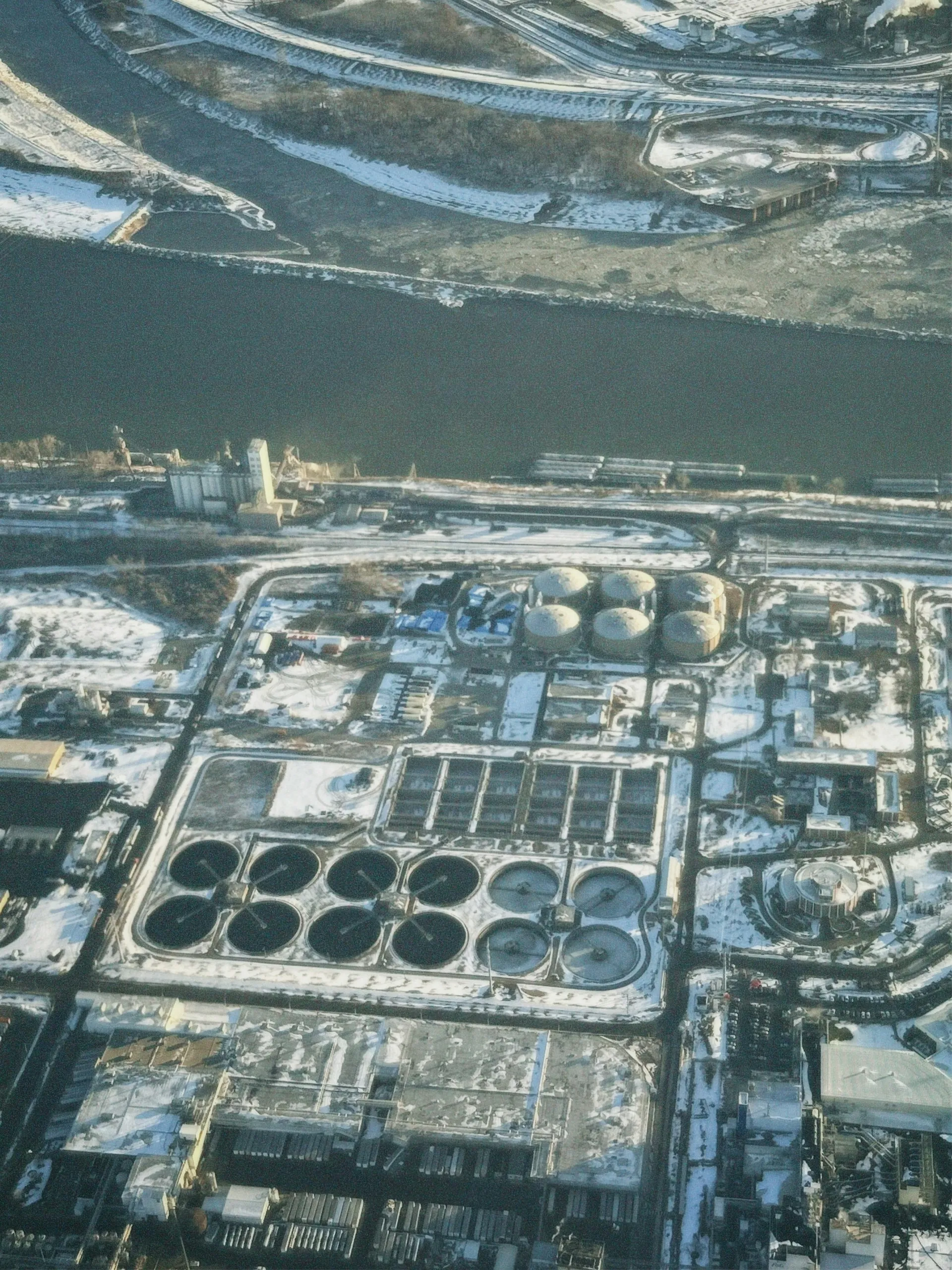 Aerial view of an industrial complex beside a river in winter