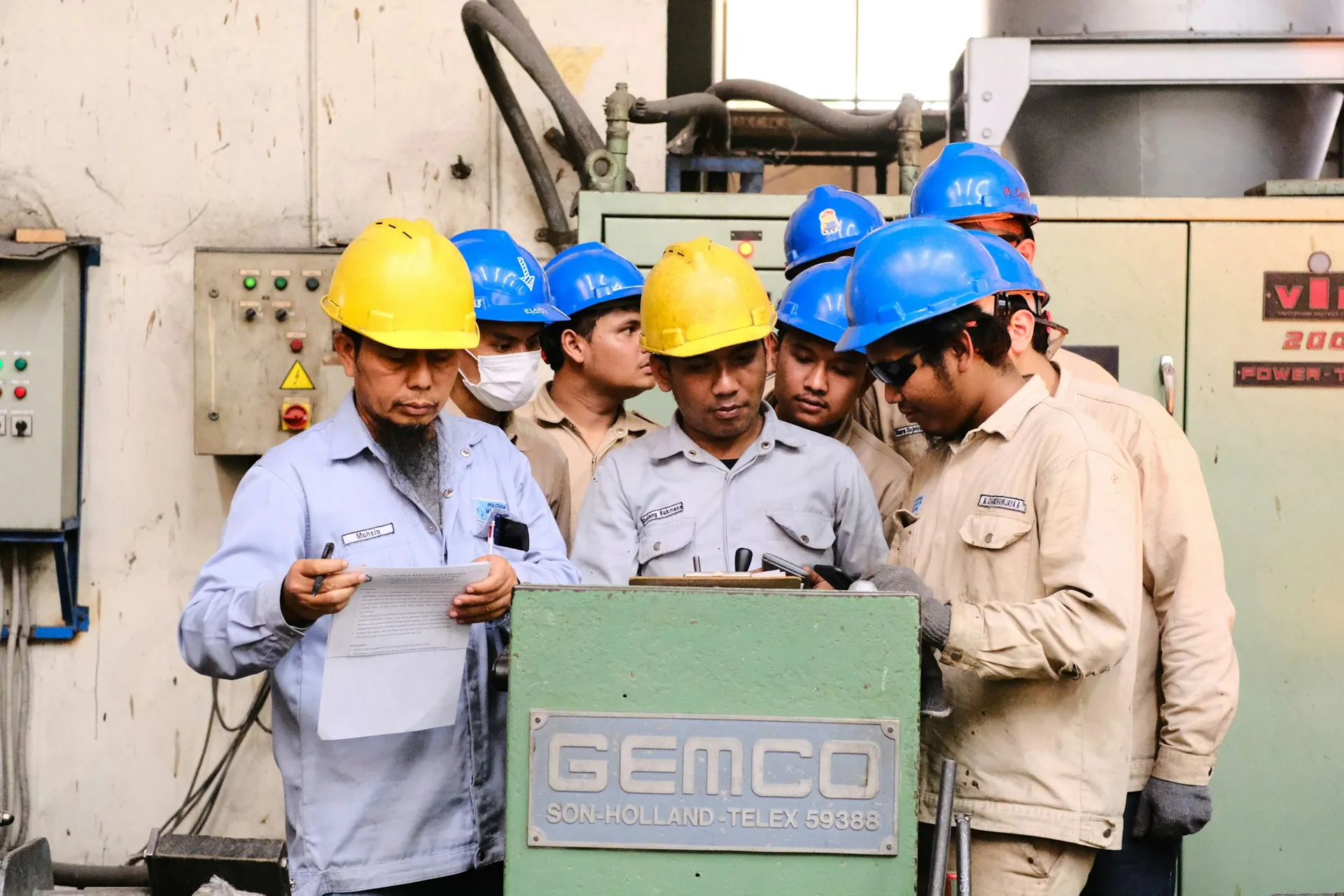 Team of technicians in hard hats reviewing a procedure beside equipment