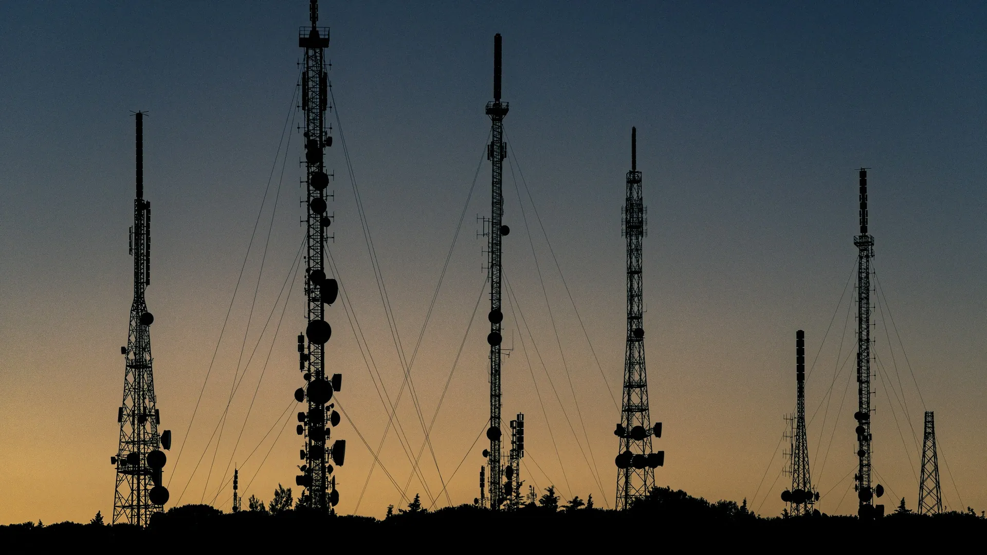 Communication towers silhouetted against a dusk sky